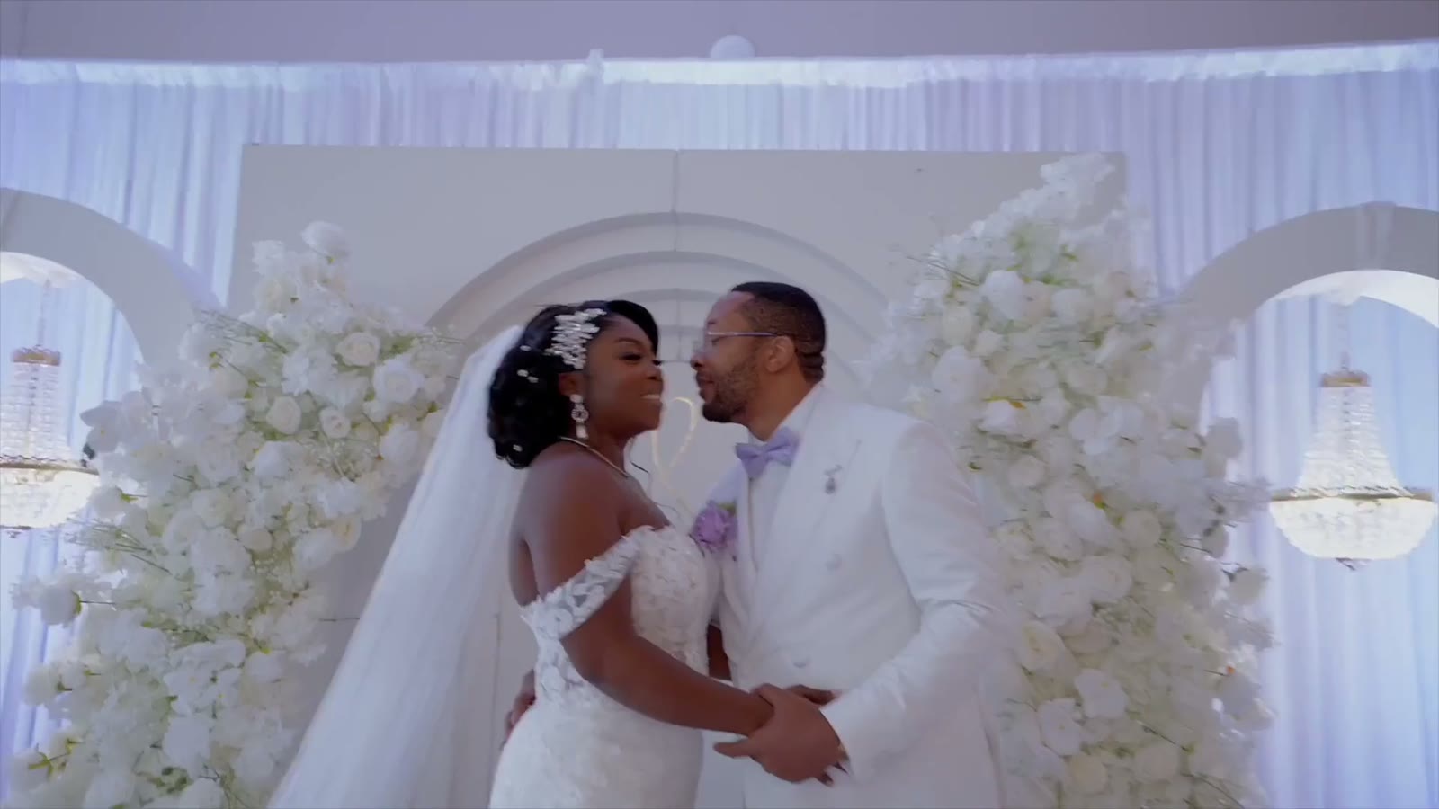 Newly married couple sharing a portrait in front of white wedding florals